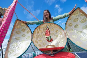 Image of a woman presenting a model of a chickpea, which opens up to reveal a dancing lady inside