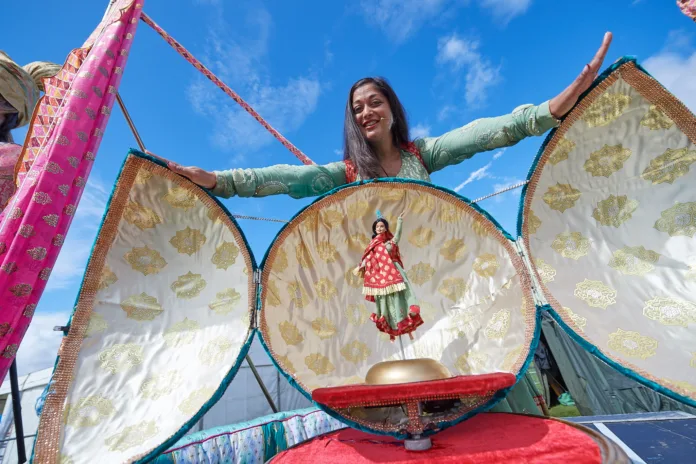 Image of a woman presenting a model of a chickpea, which opens up to reveal a dancing lady inside