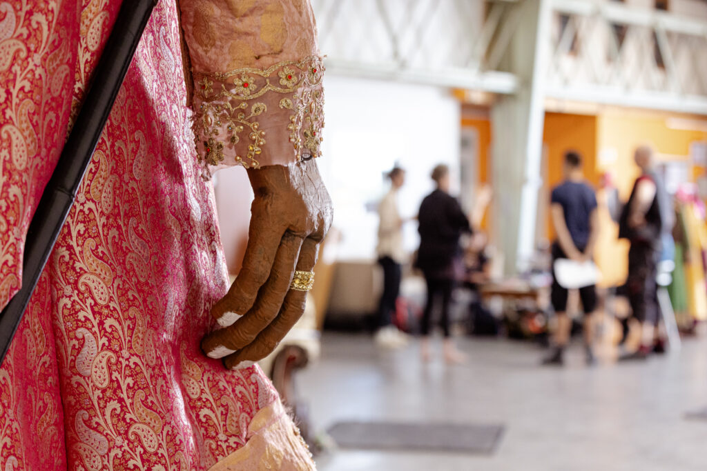 The hand of our giant puppet is in focus, with the group of performers huddled in the background