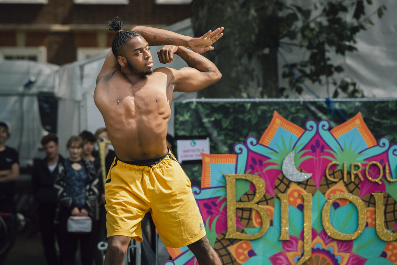 Bonetics at Bristol Harbour Festival. The performer is contorting his body and pulling his shoulder behind his head.