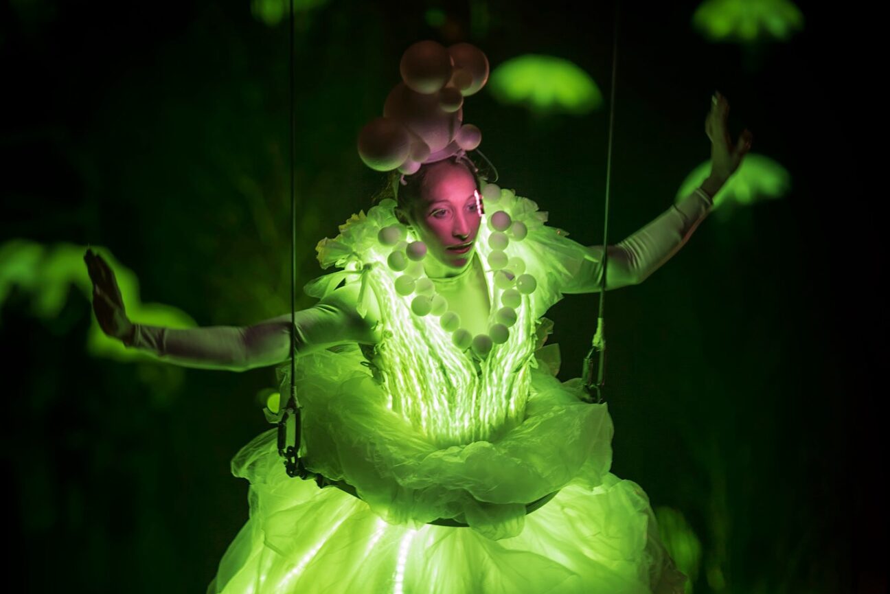 Aerialist performers in our green lit LED dress, with green umbrellas in the background