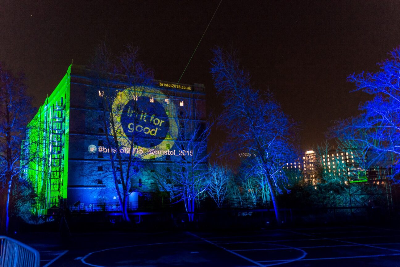 Projections light up an industrial looking building, celebrating Bristol as Green Capital