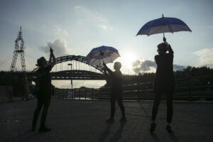 Dancers rehearse in the sunshine with umbrellas. Portolan, Sunderland Tall Ships, Cirque Bijou. Image Dan Prince.