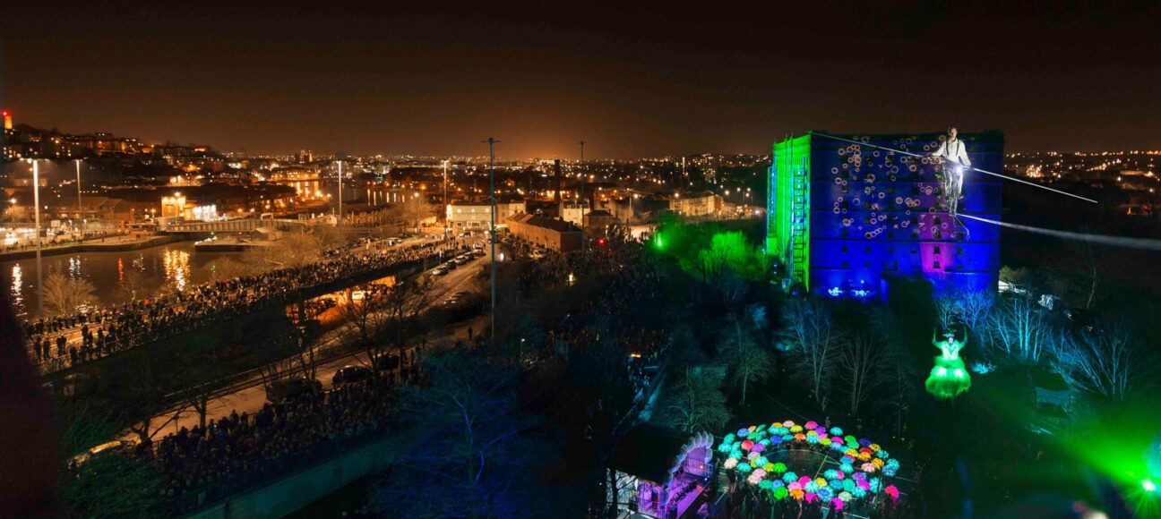 Image of the city of bristol, with projections on a building, and our LED Umbrellas in the foregound, illuminated in a circle