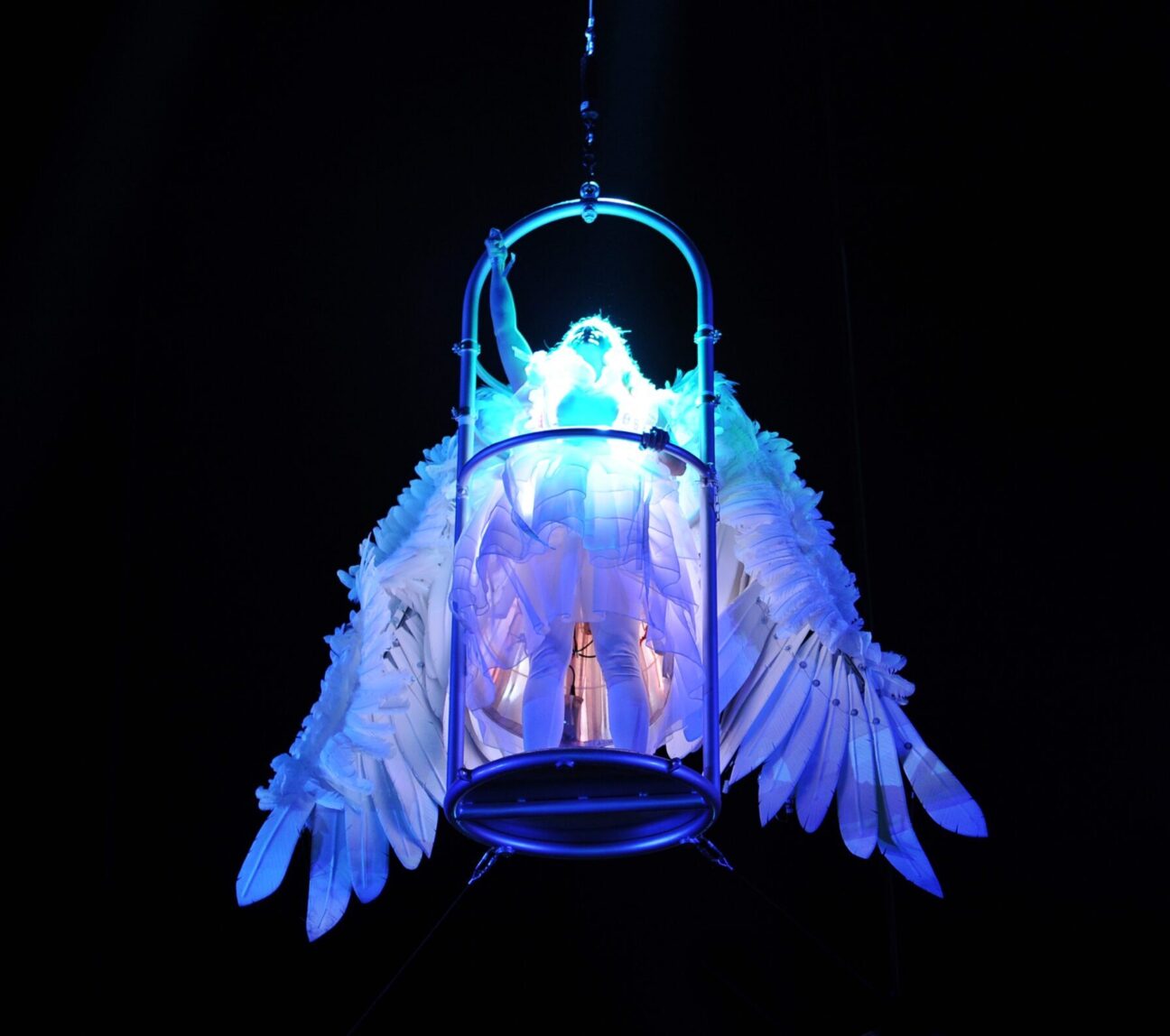 An opera singer stands in our aerial wings prop, lifted up in the sky, illuminated in our led dress