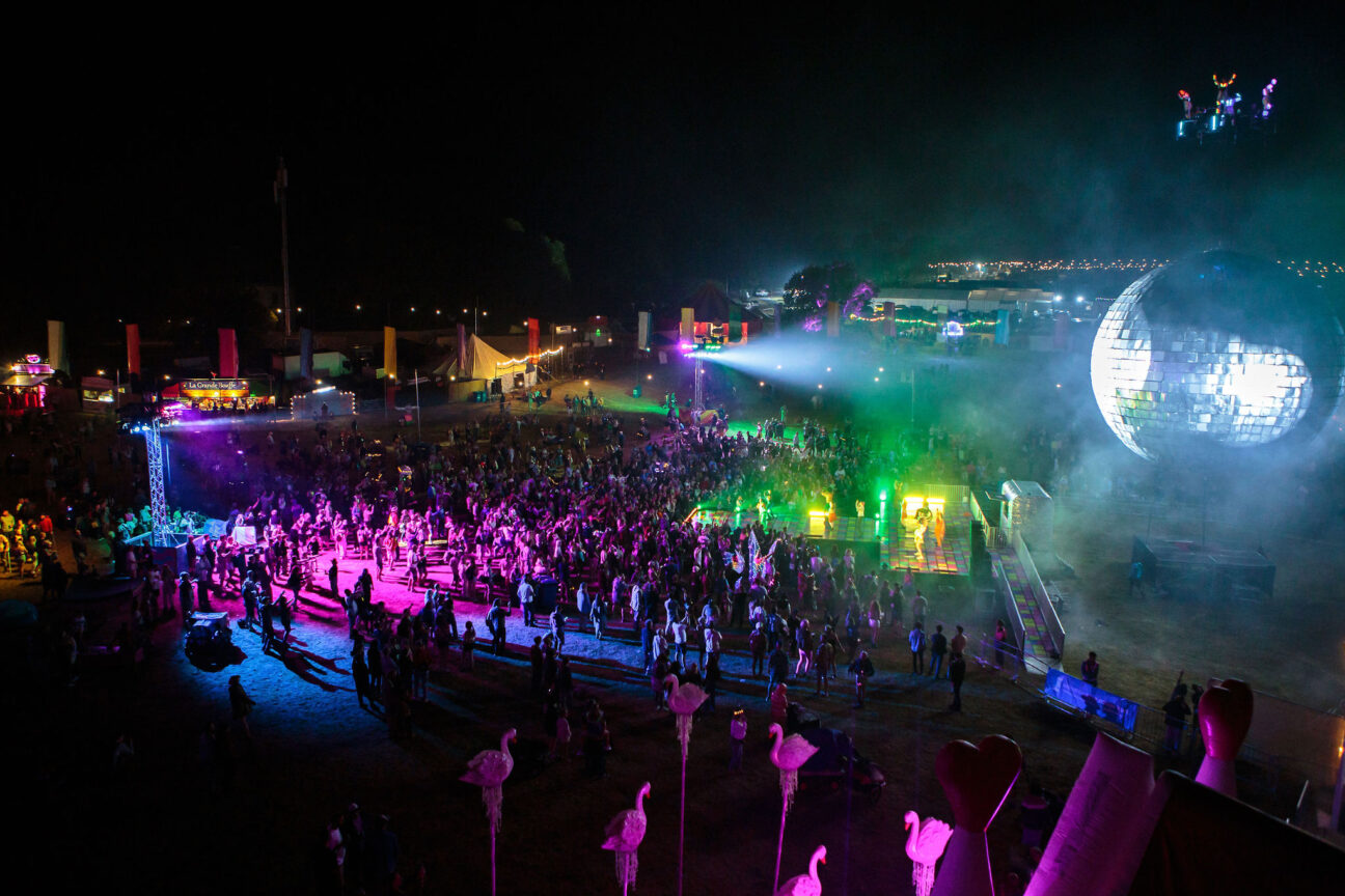 An image of the Camp Bestival stage from a distance, the giant silver disco ball and the audience.