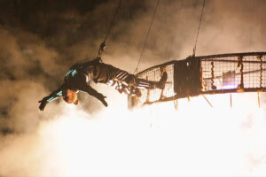 A performer hangs from the aerial crane in the skiy. 