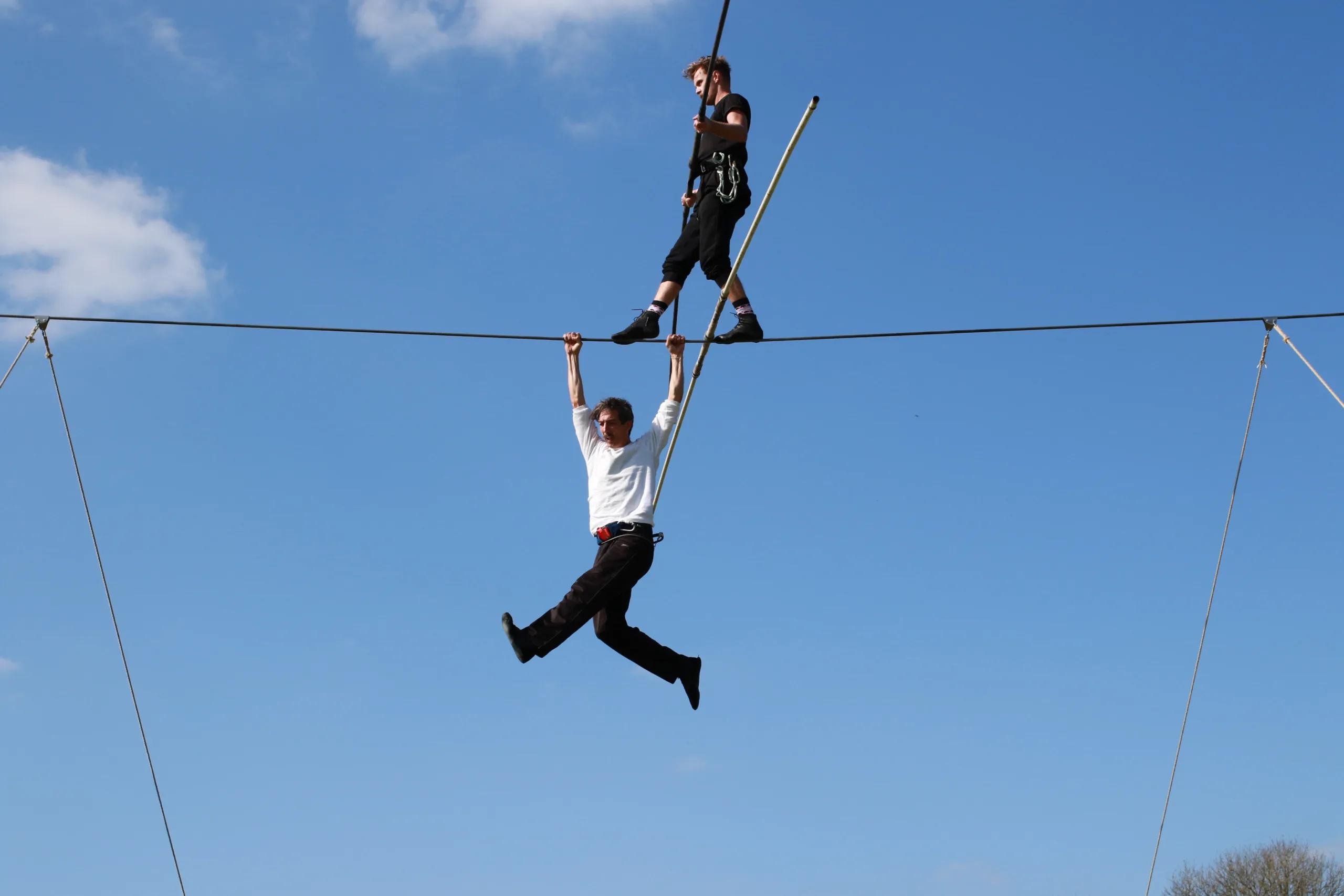 Chris Bullzini hangs from a suspended wire whilst Adam O'Connor McMahon walks above him.