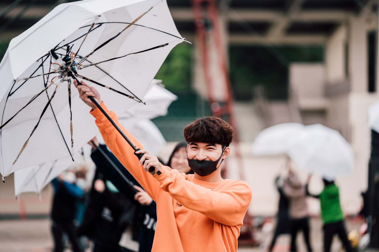 A close up shot during rehearsals of one of the umbrella dancers with a smile on his face