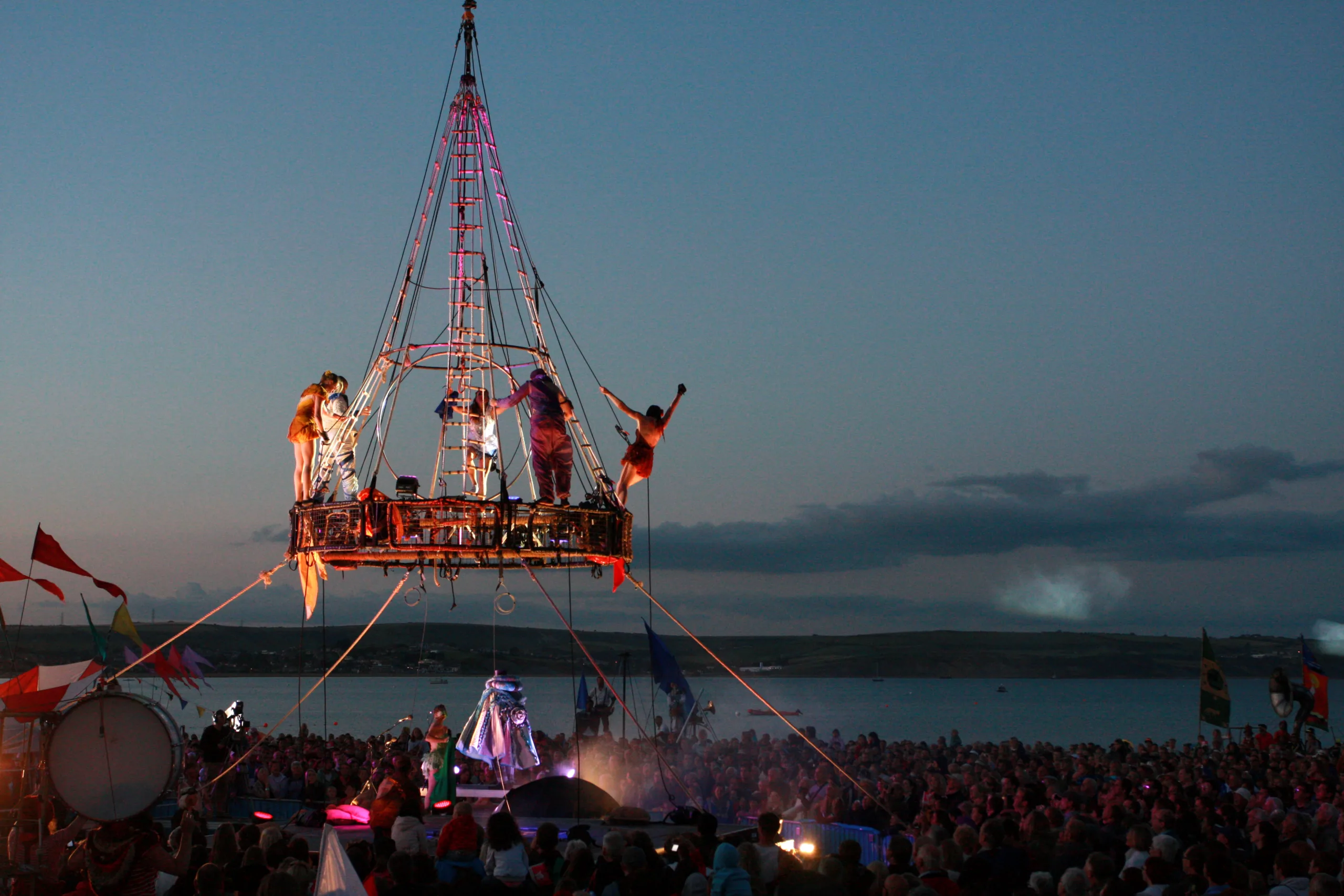 Aerialist stand ready to perform off our aerial carousel, suspended from a crane. Against a dusk night sky setting