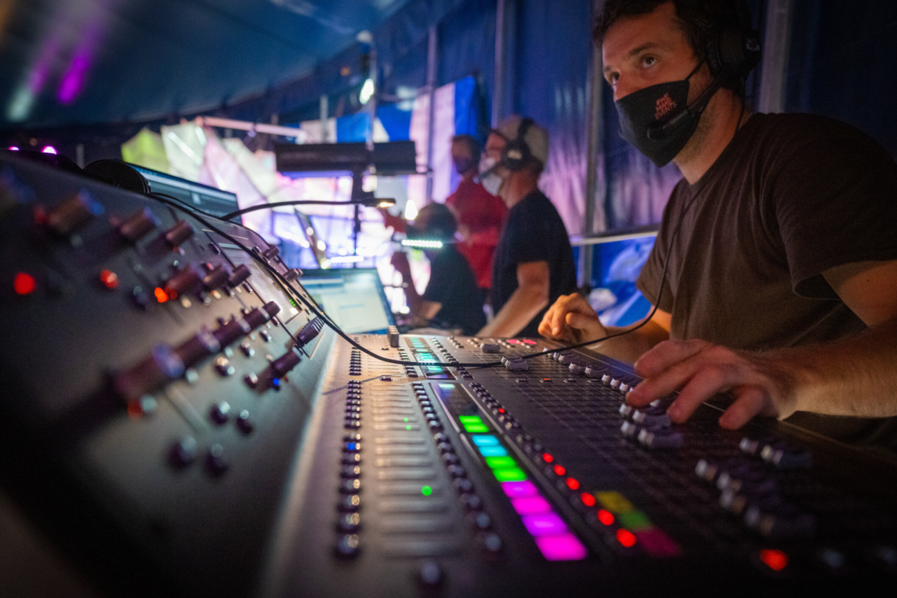 A technician hovers over his sound desk whilst watching the show