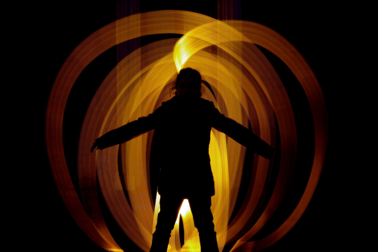 A silhouette of a person in front of orange and yellow spiralling lights.