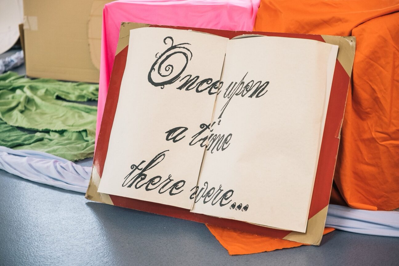 A prop of a large book that says in fancy writing "Once upon a time there were...". The book is resting on some pink and orange set.