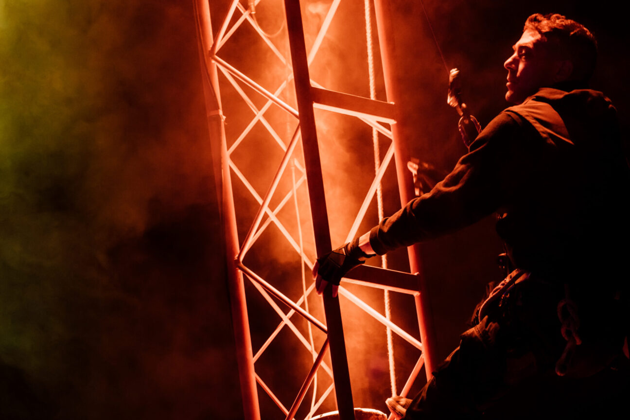 Male rigger climbing a metal structure.