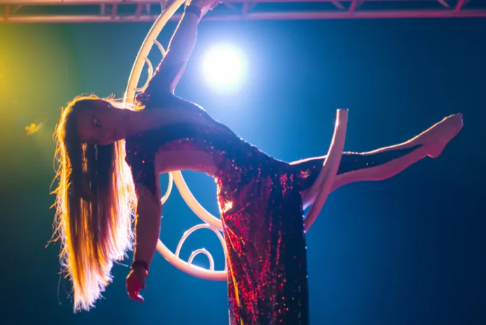 An aerialist hangs suspended in a crescent moon