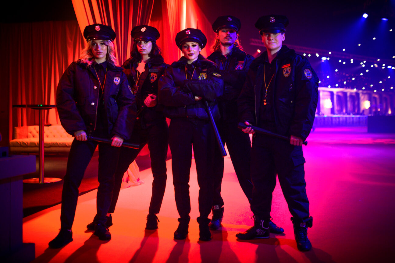 Performers dressed as NYC cops stand posed backstage, ahead of their performance