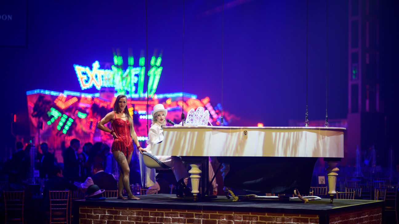 A singer and performer sit by our aerial piano, positioned on the ground